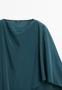 Tealfarbene, drapierte Bluse aus einem glatten, glänzenden Stoff. Hat einen weiten Ausschnitt und einen fließenden, asymmetrischen Saum. Etikett am Hals sichtbar.