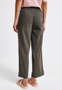 Pantalons verts à jambes larges avec une coupe décontractée et une taille élastique. Comprend deux poches arrière et un design de bas de pantalon retroussé. Texture de tissu douce.