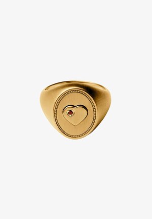 Anillo sello de oro con una forma de corazón grabada centrada dentro de un borde ovalado, con una pequeña piedra preciosa roja en el lado superior izquierdo del corazón.