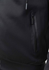 Veste noire texturée avec une poche zippée dotée d'unzip agréable, de finitions délicates et d'un design ajusté.