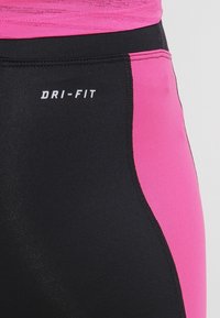 Černé a růžové Dri-Fit legíny s elegantním designem. Obsahují kontrastní panely, hladkou texturu a přiléhavý střih.