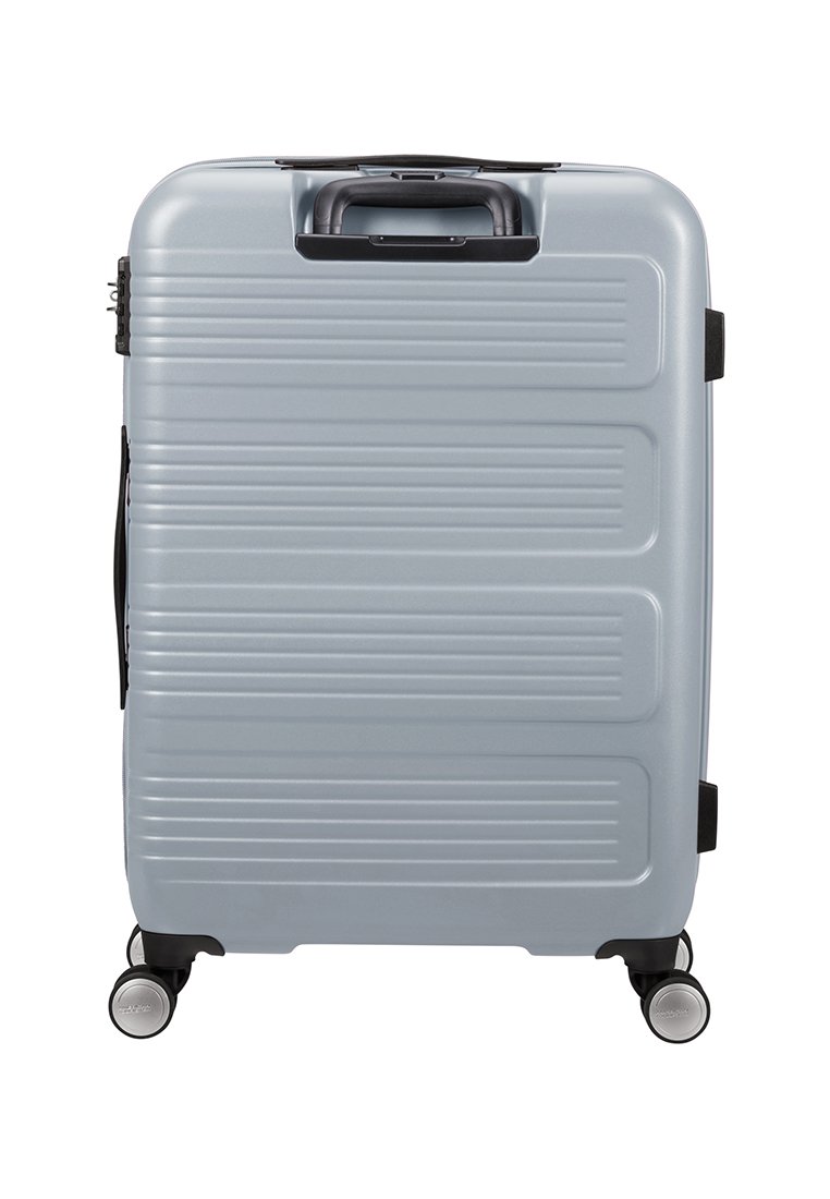 Maleta rígida plateada con estrías horizontales, asas retráctiles y cuatro ruedas. Presenta un cierre seguro y acentos en negro.
