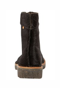 Botín negro hasta el tobillo con textura de piel de pelo, material suave, puntera redondeada, tacón bajo y apilado, y puño ligeramente doblado en la parte superior.