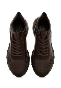 Zapatillas de cuero marrón con una superficie texturizada, con punta redondeada, diseño con cordones y una suela gruesa y maciza con detalles angulares.