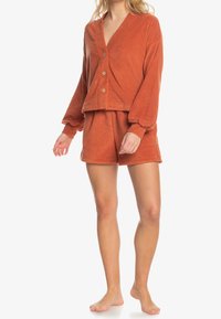 Przytulny zestaw do noszenia w domu w kolorze rdzy, składający się z przyciskiwanego topu z dekoltem w serek i długimi rękawami oraz dopasowanych szortów. Miękka tkanina o teksturowanym wykończeniu.