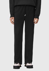 Czarne dresy o luźnym kroju, z regulowanym sznurkiem w pasie i miękką teksturą materiału. Charakteryzują się minimalistycznym designem bez wzorów czy akcentów.