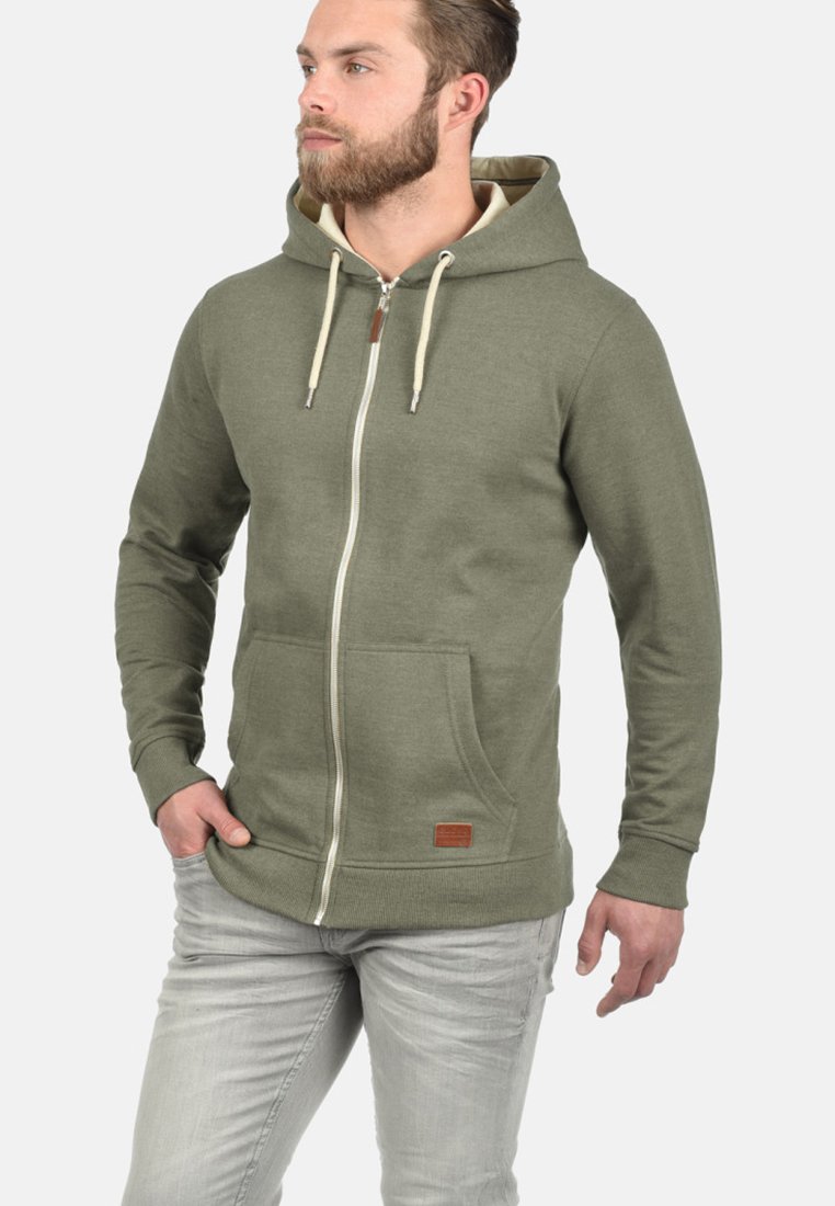 Olivgrüner Zip-Hoodie aus Baumwollmischung, mit Kapuze inklusive Kordelzug, Fronttaschen und einem Logo-Patch aus Kunstleder.