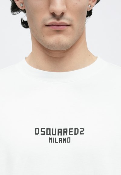 Felpa bianca con collo rotondo e polsini a costine, con un logo nero prominente al centro che dice "DSQUARED2 MILANO".
