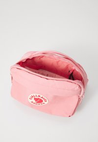 Roze stoffen zippered tas met een wit rond logo met een vos. Voorzien van een stevige handgreep en een ruime binnenkant met een gladde textuur.