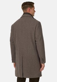 Cappotto a motivo a spina di pesce in un colore marrone tenue; presenta un colletto a punte, maniche lunghe e polsini abbottonati. Design pulito e sartoriale.