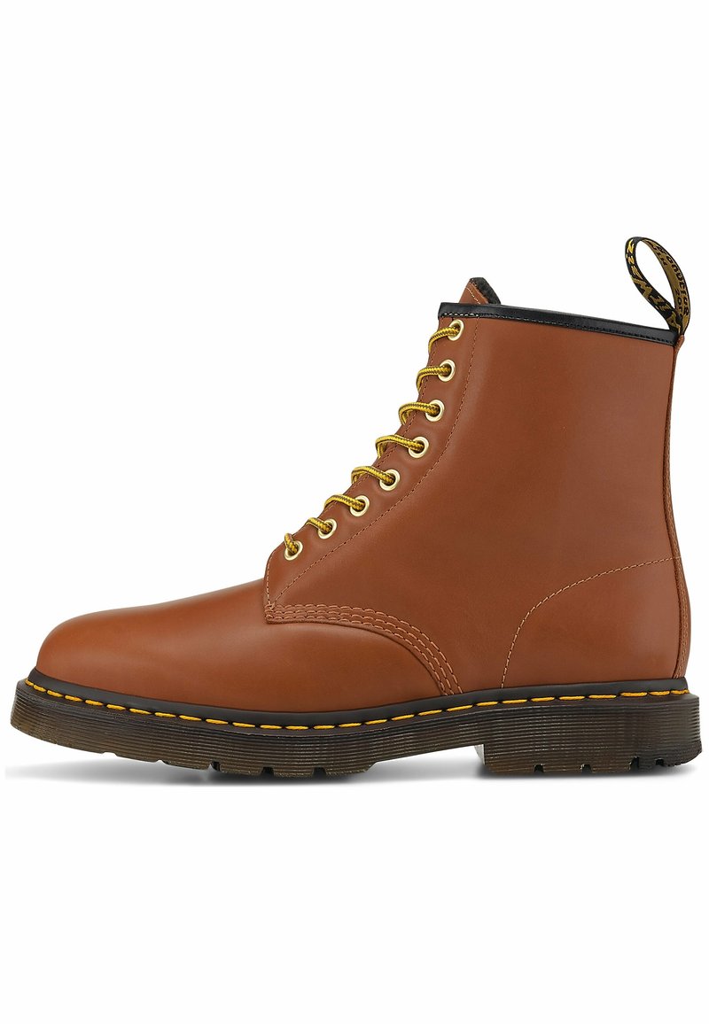 Bottine en cuir marron avec lacets jaunes, semelle noire avec coutures jaunes et languette de talon marquée.