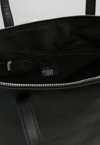 Černá taška přes rameno se zipovým uzávěrem, hladkým koženým vnějším povrchem a textilním podšívkou. Uvnitř se nachází zipová kapsa a označení značky.