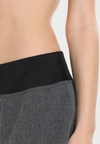 Grijze sportbroeken met een brede zwarte tailleband. De stof is gemêleerd en het ontwerp heeft een casual, aansluitende vorm zonder patronen.