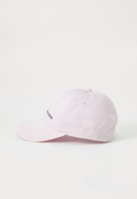 Casquette de baseball rose clair à visière courbée, arborant un logo noir brodé sur le côté, fabriquée en tissu lisse avec des œillets de ventilation.