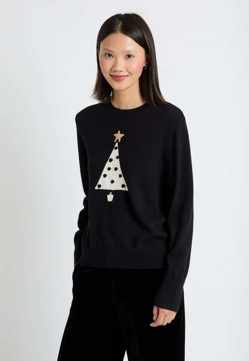 Pull noir avec un design de sapin de Noël crème, des pois noirs et une étoile dorée en accent en haut. Manches longues, coupe décontractée.