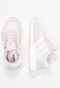 Rosa sportskor i mocka och meshmaterial, med tre vita ränder, rund tå och strukturerad gummisula.