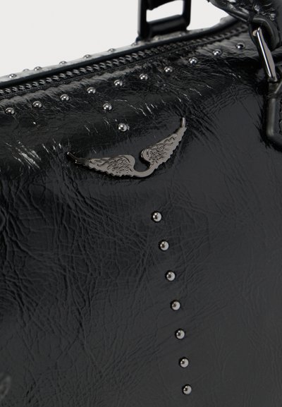 Τσάντα από μαύρο δερματίνη με διακοσμητικά καρφιά και έμβλημα σε σχήμα φτερού. Διαθέτει φερμουάρ και υφή στην επιφάνεια. Εντυπωσιακά γυαλιστερά καρφιά.