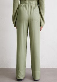 Green wide-leg pants with an elastic waistband, smooth texture, and a back pocket. The fabric is lightweight and has a subtle sheen.