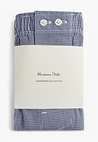 Boxers à carreaux bleus et blancs pliés et emballés avec un banderole blanche étiquetée "Collection de sous-vêtements Massimo Dutti", comportant deux boutons.