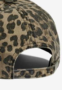 Gorra con estampado de leopardo, con un tejido texturizado en caqui y negro, que cuenta con una correa ajustable y un clip de metal en la parte trasera.