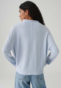 Hellblauer Strickpullover mit einer strukturierten Musterung, lockerem Sitz und langen Ärmeln. Verfügt über eine Naht auf der Rückseite und gerippte Bündchen.