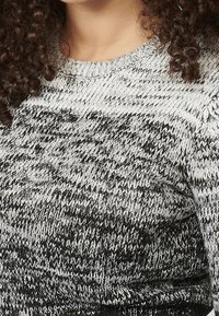 Sweter dziergany z szaro-czarnym gradientowym wzorem, z okrągłym dekoltem i teksturowaną tkaniną z widocznym przeszyciem.