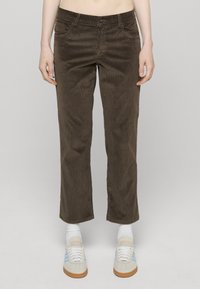 Brune kordfløyelsbukser med rett ben, med frontlommer og en subtil ribbestruktur. Enkel midje med knappelukking.