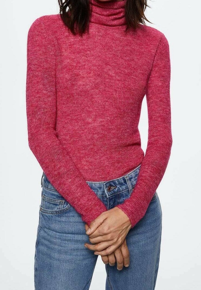 Pull à col roulé en maille texturée rose, manches longues, coupe ajustée. Associé à un jean bleu taille haute avec une fermeture par boutons.