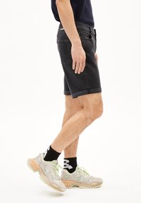 Zwarte denim shorts met een opgerolde zoom, slim fit en vijfzakken ontwerp. Gecombineerd met lichte sneakers met doorzichtige accenten en een dikke zool.