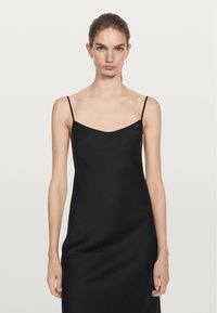 Černé šaty na tenkých ramínkách, hladký saténový materiál, přiléhavý silueta, jemný výstřih do V, dlouhé až na zem, minimalistický design bez ozdob.