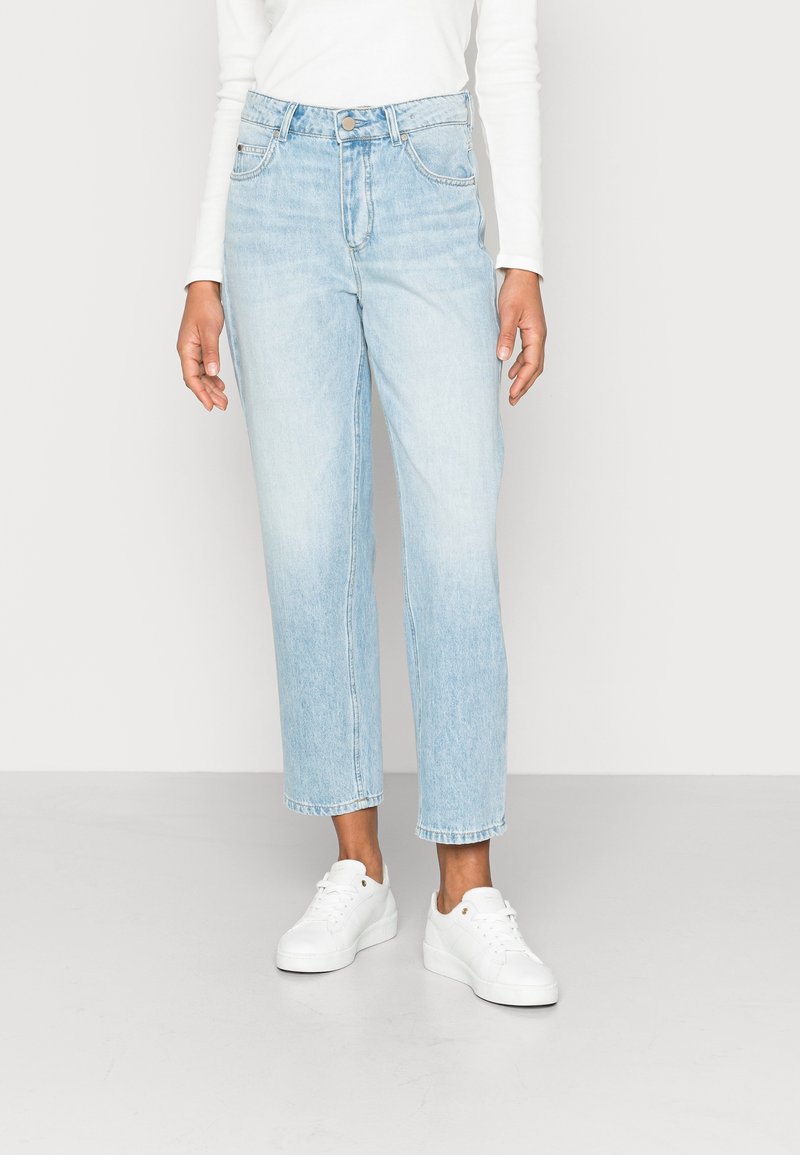 Ljusblå denimjeans med hög midja, rak ben och något kortad längd. Kombinerade med vita sneakers.