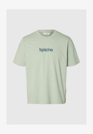 Heleroheline lühikeste varrukatega T-särk, ümar kaelus, sinise stiliseeritud tekstiga "lapiscine" rinnal keskel.