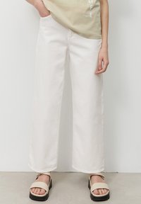 Vita vida jeans i bomullstyg med hög midja. Kombinerat med beige plattformssandaler med ett band över tårna.