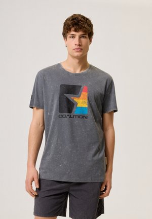 Szary t-shirt z krótkim rękawem o postarzanym wykończeniu, z kolorową graficzną gwiazdą i napisem "KOALICJA" czarnym pod nią.