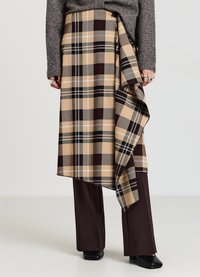 Gonna a quadri in beige, marrone e verde con design drappeggiato, dotata di chiusura con bottoni e orlo sovrapposto, abbinata a pantaloni marroni.