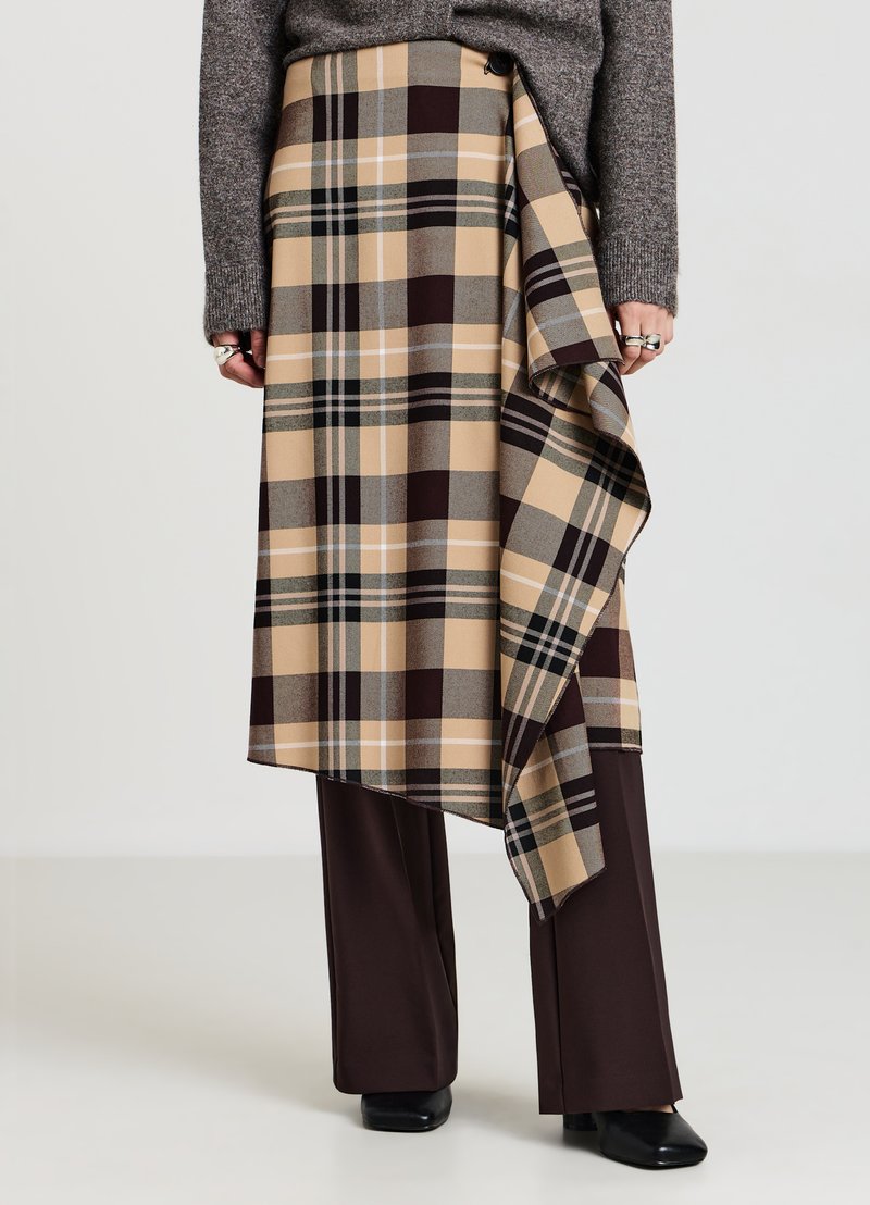 Gonna a quadri in beige, marrone e verde con design drappeggiato, dotata di chiusura con bottoni e orlo sovrapposto, abbinata a pantaloni marroni.