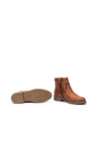 Brown leather ankle boots with a side zipper, round toe, and stacked heel. Textured rubber sole with patterned grip detailing.