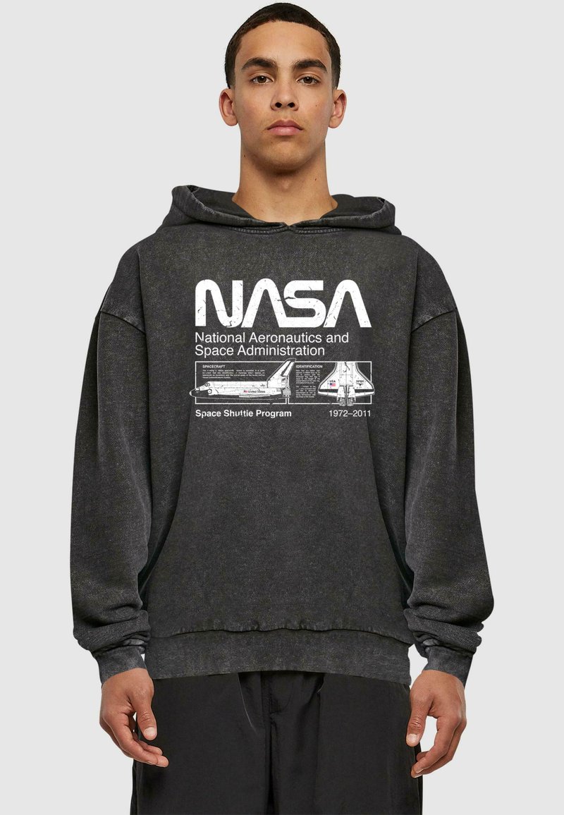 Sweatshirt en coton gris avec capuche, comportant un grand logo NASA blanc et des détails de mission imprimés sur le devant. Design ample.