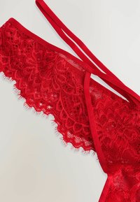 Rød blonde lingeri med blomsterdesign, der har et glat rød elastisk bånd og intrikate kanter. Letvægts med en delikat struktur.
