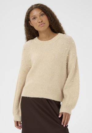 Strickpullover in hellem Beige mit Rundhalsausschnitt, der perlenähnliche Verzierungen an den Ärmeln und gerippte Bündchen aufweist. Glatte Textur und lockere Passform.