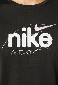 Svart tyg med stora vita Nike-text och rosa swoosh-logotyp, omgiven av vita geometriska linjedesign som liknar konstellationer.