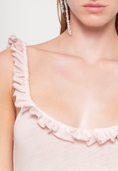 Top rosa chiaro con bordi arricciati lungo il colletto. Tessuto morbido messo in risalto da una leggera lucentezza. Primo piano che si concentra sull'area del torso.