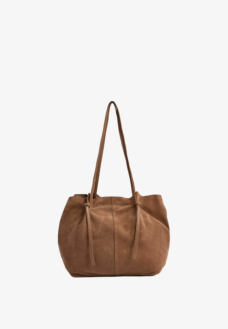 Bruine suède totebag met twee lange handvatten, ronde vorm en trekkoordsluiting. Kenmerkt zich door een zachte textuur en een minimalistisch ontwerp.