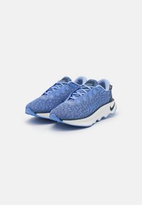 Niebieskie sportowe sneakersy z teksturowaną dzianinową cholewą, sznurowanym zapięciem, zaokrągloną podeszwą oraz subtelnymi akcentami logo w bieli i granacie.