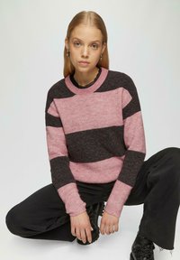 Roze en donkergrijs gestreepte trui met een geribbelde textuur en een ronde halslijn, gecombineerd met zwarte broek en kantaccenten.