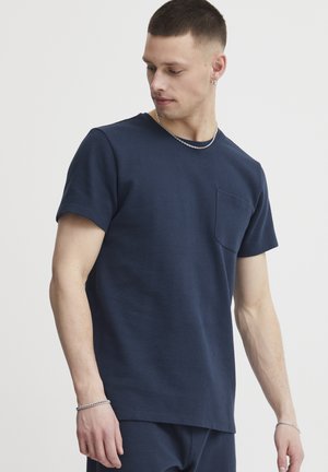 Tricou din bumbac bleumarin cu guler rotund, realizat dintr-un material texturat, având mâneci scurte și un buzunar pe pieptul stâng. Croială casual cu linii curate.