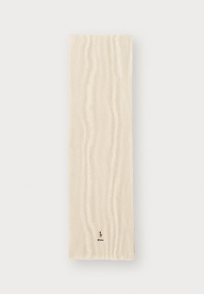 Beige ribbesjal med en myk tekstur, med en liten brodert logo nederst. Enkel rektangulær form uten mønster.