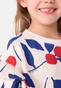 Cremefarbener Sweatshirt mit buntem Blumenmuster in Rot und Blau. Weicher Stoff mit Rundhalsausschnitt und leicht gepufften Ärmeln.