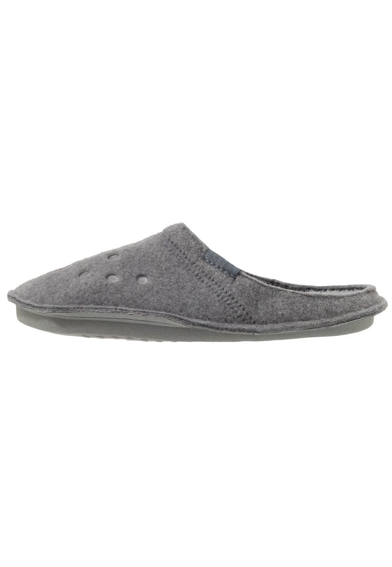 Zapatilla gris de felpa con suela de goma suave, que presenta agujeros de ventilación, punta redondeada y un forro texturizado. Diseño simple y fácil de poner.