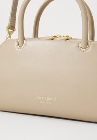Borsa a tracolla in pelle beige con due manici tondi, accessori in oro e logo impresso. Texture liscia con dettagli di cucitura sottili.